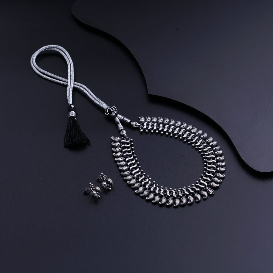 a necklace and earring with a tassel on a black surface