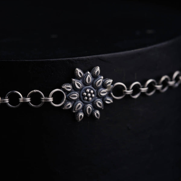 a close up of a metal chain with a flower on it