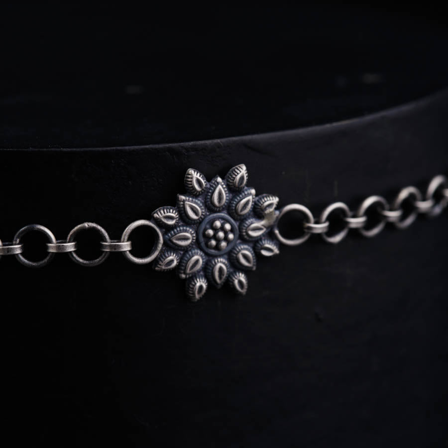 a close up of a metal chain with a flower on it