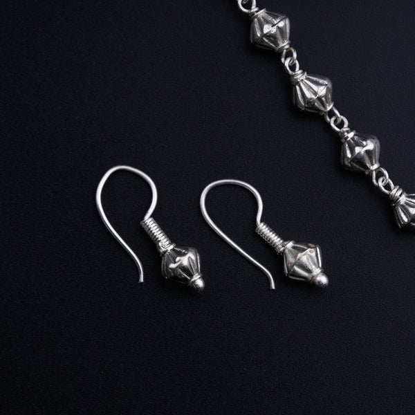a pair of silver earrings on a black surface