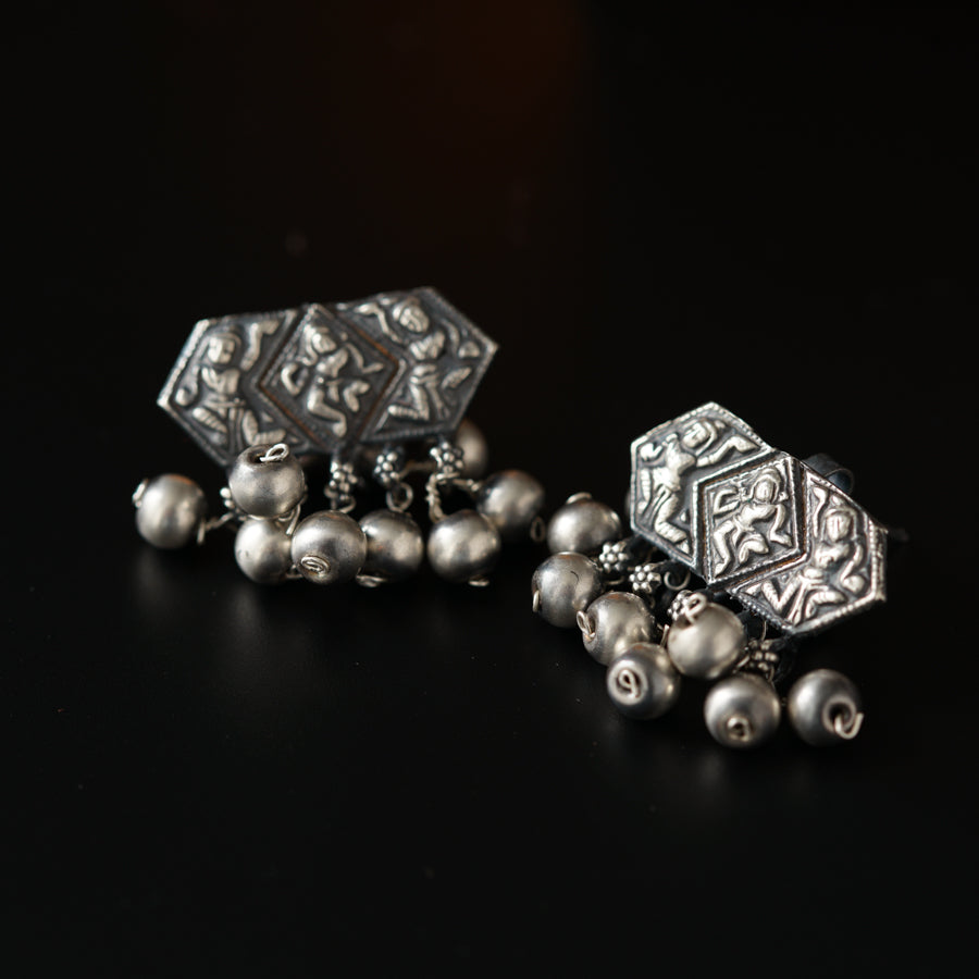a pair of silver earrings on a black surface