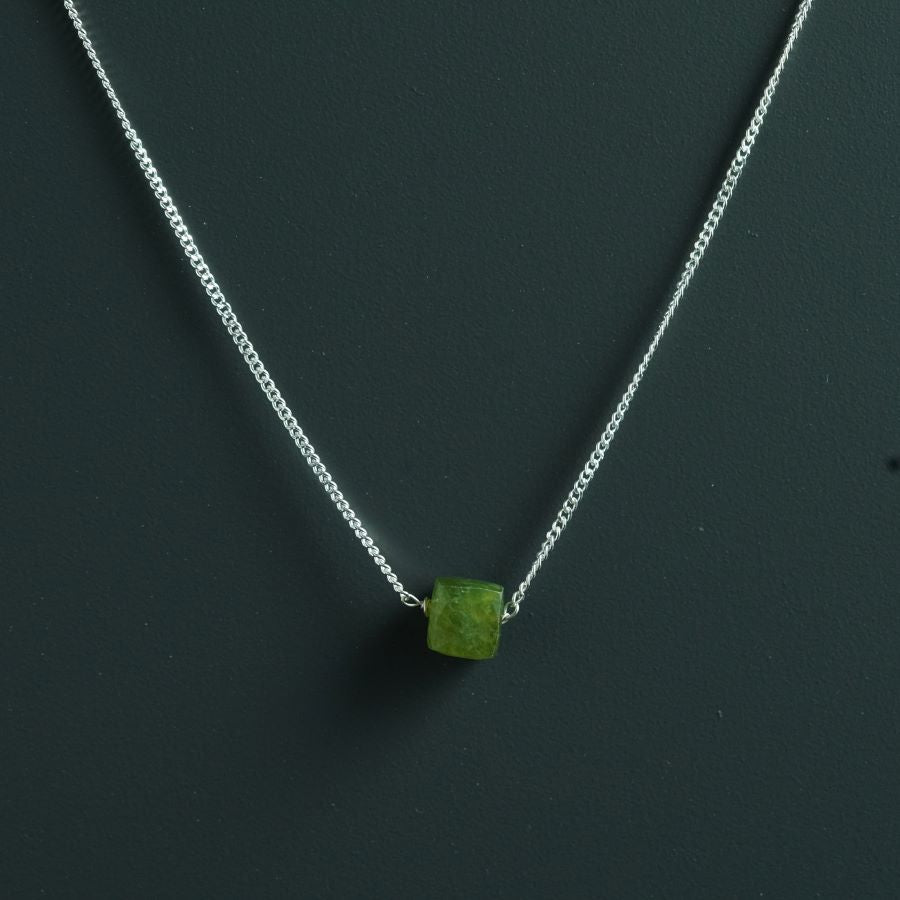 a necklace with a green stone on a chain