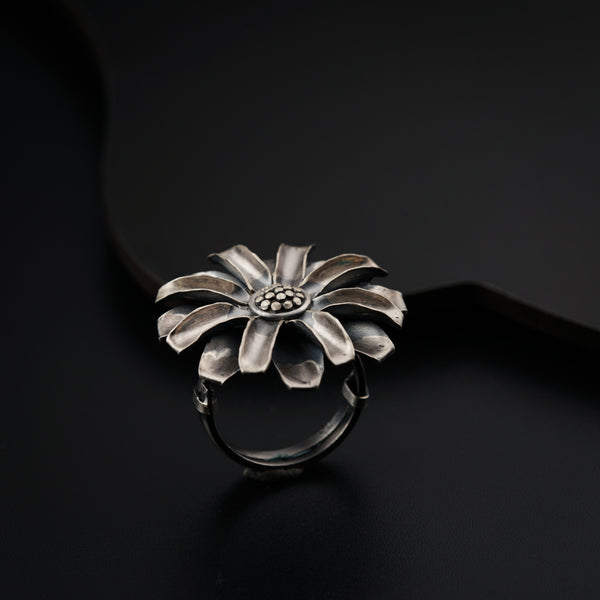 a silver flower ring sitting on top of a black surface