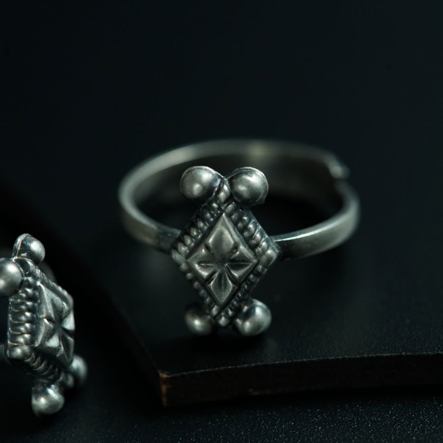 a silver ring and a silver turtle on a black surface