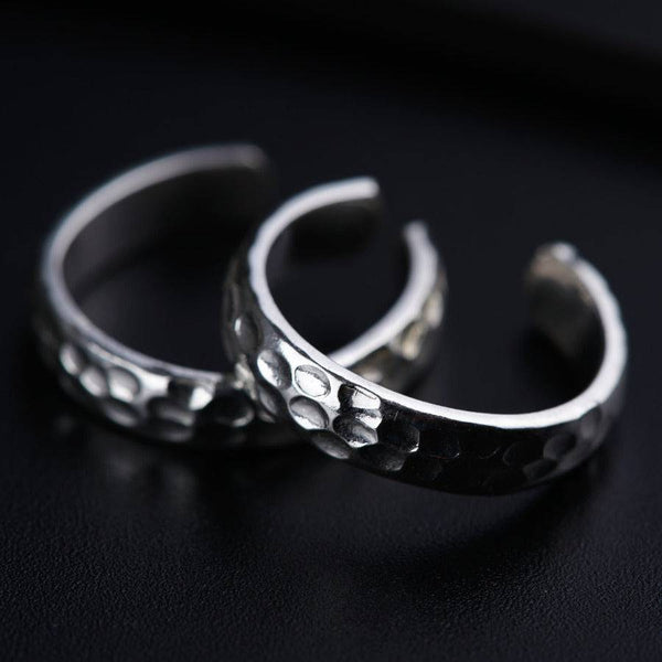 two silver rings sitting on top of a black surface