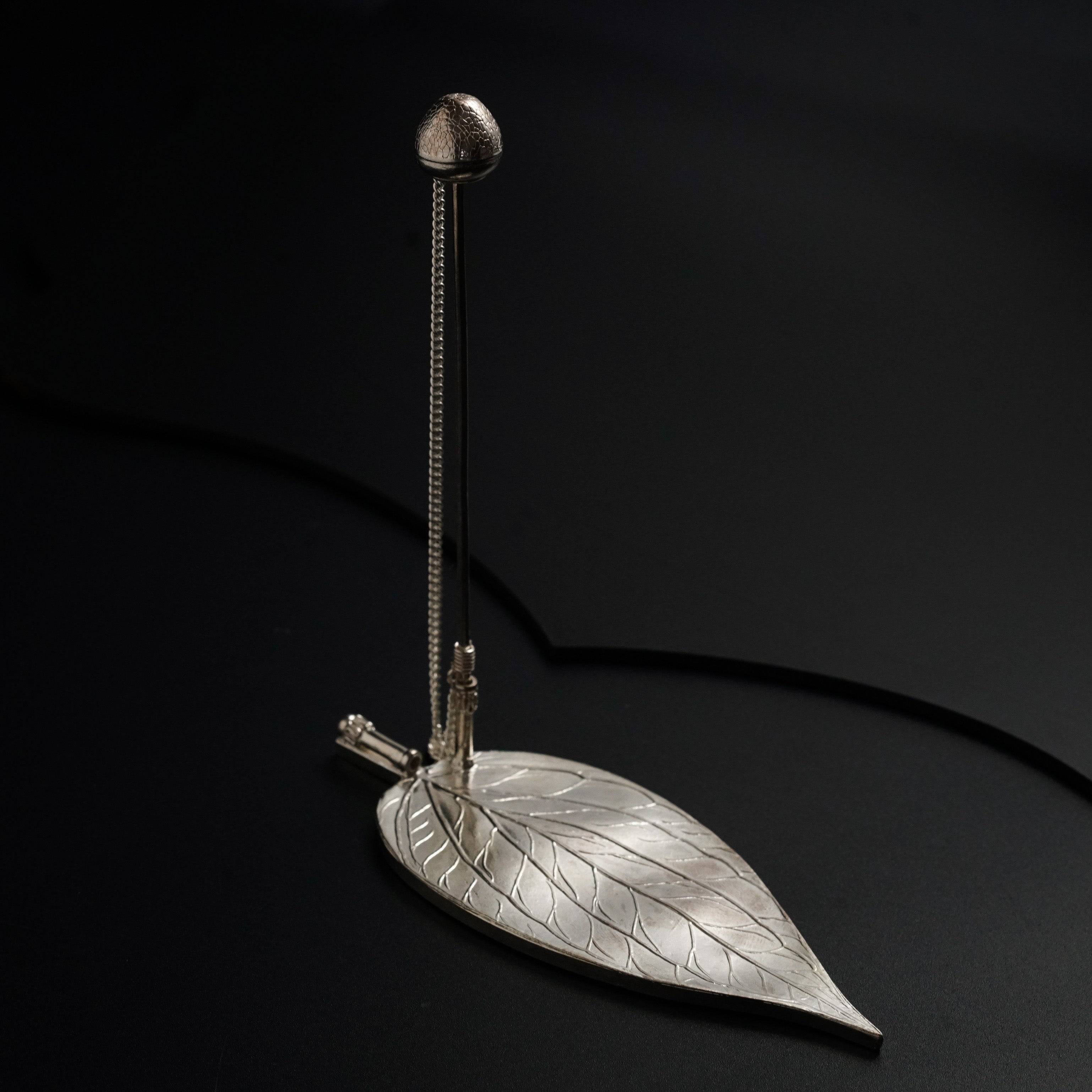 a metal object with a leaf on it